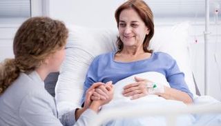 فتاة تأخذ بيد سيدة مريضة بالسرطان