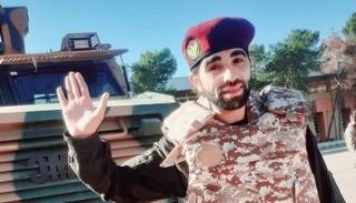 أحد المرتزقة السوريين يلوح أمام ناقلة جند مدرعة تركية في طرابلس