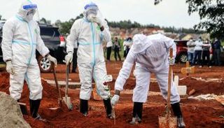 أشخاص يرتدون بدلات واقية في مقبرة