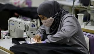 امرأة تخيط كيسا معدا لدفن موتى كورونا في مشغل الأم بمدينة صيدا جنوب لبنان