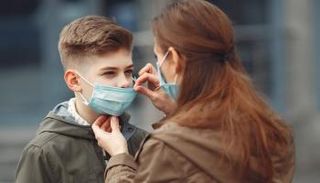 امرأة تضبط الكمامة على وجه طفل