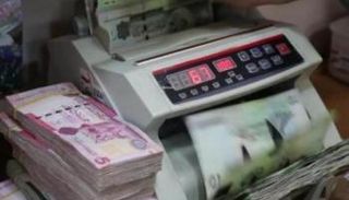 موظف بأحد مصارف ليبيا يحصي أوراقًا من فئة الـ10 دينارات. (أرشيفية)