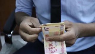 موظف بأحد مصارف ليبيا يحصي أوراقًا من فئة الـ20 دينارًا. (أرشيفية)