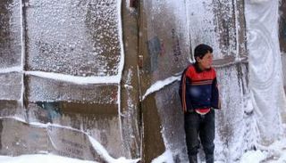 طفل سوري يقف أمام خيمة في طقس بارد (أرشيفية)