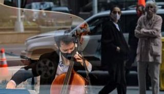 عازف تشيللو يعزف الموسيقى من خلف زجاج متجر