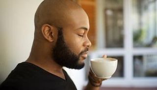 رجل يشم رائحة فنجان قهوة
