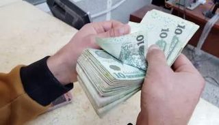 موظف بأحد مصارف ليبيا يحصي أوراقًا من فئة الـ10 دينارات. (أرشيفية)
