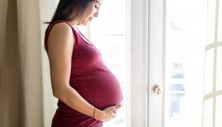 سيدة حامل تنظر بسعادة إلى الجنين في بطنها