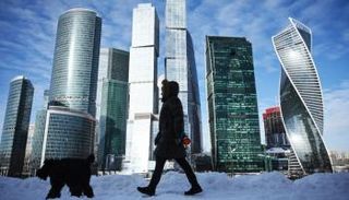 امرأة تنزّه كلبها أمام مباني مركز الأعمال الدولي في موسكو