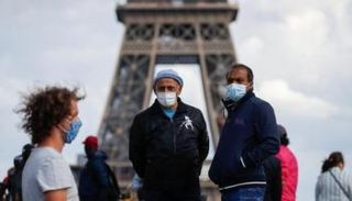 مواطنون فرنسيون يرتدون كمامات أمام برج إيفل