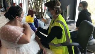 العروس سارة ستودلي أثناء تلقيها لقاح كورونا وهي مرتدية فستان زفافها