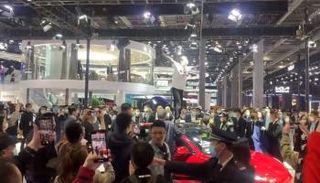 سيدة تعتلي سيارة تسلا في معرض شنغهاي