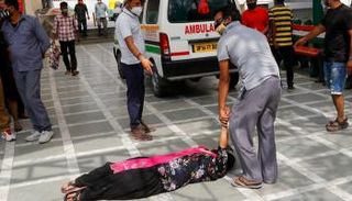 رجل يحاول مساعدة سيدة مصابة بفيروس كورونا على النهوض