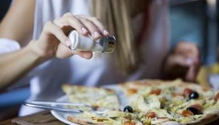 امرأة تضع ملحا على طبق بيتزا