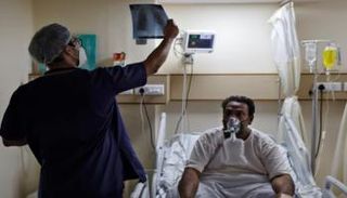 طبيب يفحص الأشعة السينية لمريض كورونا بالهند