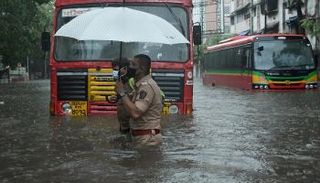 شرطي يساعد سائق نقل عام على عبور شارع غمرته المياه في مومباي