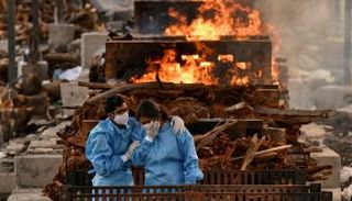 أقارب أحد المتوفين بفيروس كورونا يحضرون مراسم حرق جثمانه في الهند