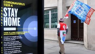رجل يمر بجوار لافتة تدعو إلى البقاء في المنزل للوقاية من فيروس كورونا