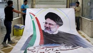 عمال يطبعون صورة للمرشح المتشدد إبراهيم رئيسي