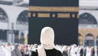 سيدة تقف أمام الكعبة الشريفة