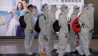 مسافرون يرتدون ملابس واقية من فيروس كورونا في مطار هونج كونج