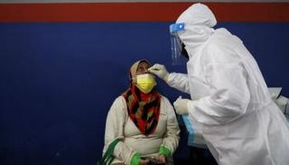 عامل صحي يأخذ مسحة من امرأة في ماليزيا