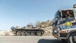 دبابة متضررة على جانب طريق أثناء مرور شاحنة تابعة لقوات أمهرة الخاصة