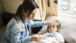 أم تقيس درجة حرارة طفلتها المريضة