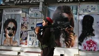عنصر من طالبان أمام واجهة مشوهة لأحد محلات كابول