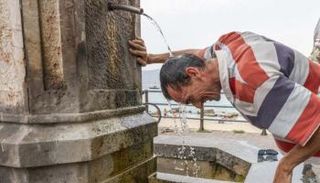 رجل ينعش نفسه في نافورة خلال يوم صيفي حار في ميسينا بإيطاليا (أرشيفية)