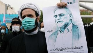 أحد الإيرانيين يحمل صورة للعالم الإيراني زاده