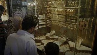سوريون يشاهدون مشغولات ذهبية معروضة في متجر بدمشق القديمة 