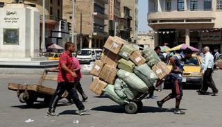 عامل يسحب عربة بضائع عند مركز تجاري وسط بغداد