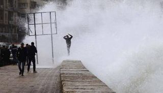 شاب مصري على كورنيش الإسكندرية أثناء هبوب أمواج شديدة - أرشيفية