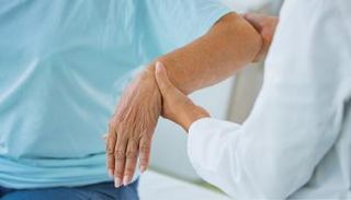 طبيب يفحص يد مريضة بالتهاب المفاصل - أرشيفية