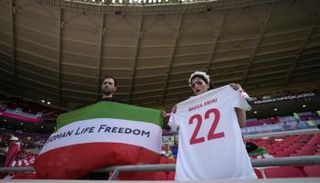 مشجعان داخل استاد أحمد بن علي يحملان لافتة داعمة لاحتجاجات إيران