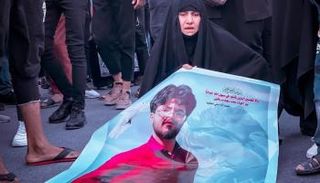 سيدة عراقية تحمل صورة نجلها خلال ذكرى 