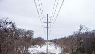 تساقط الثلوج على الأرض بالقرب من خطوط الكهرباء في ولاية تكساس