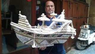 عدنان يحمل إحدى التحف التي صنعها من الصدف