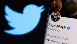 حساب Elon Musk على Twitter على هاتف ذكي أمام شعار تويتر - رويترز