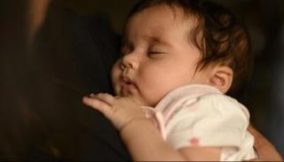 أم تحمل طفلها الرضيع