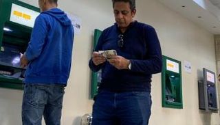 مواطنون يقومون بعمليات سحب من ماكينات صراف آلى تابعة للبنك الأهلي