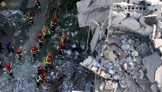 عمال الإنقاذ يعملون في مبنى سكني في ميكولايف بأوكرانيا - رويترز