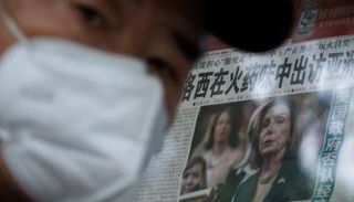 صيني أمام صحيفة معروضة تتناول زيارة بيلوسي المحتملة لتايوان