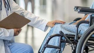 طبيب يفحص مريضاً على كرسي متحرك (أرشيفية)