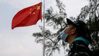 عنصر بفريق مكافحة الطوارئ الصيني يشخص ببصره لعلم بلاده