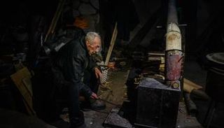 رجل يشعل الحطب في أحد الملاجئ الأوكرانية