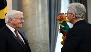 الرئيس الألماني يقف مبتسما أمام إحدى الدمى - رويترز