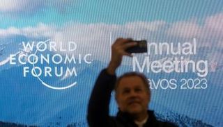 رجل يلتقط صورة أمام شعار المنتدى الاقتصادي العالمي في دافوس