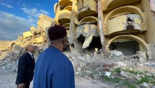 باتيلي أمام منازل دمرها الصراع في سرت